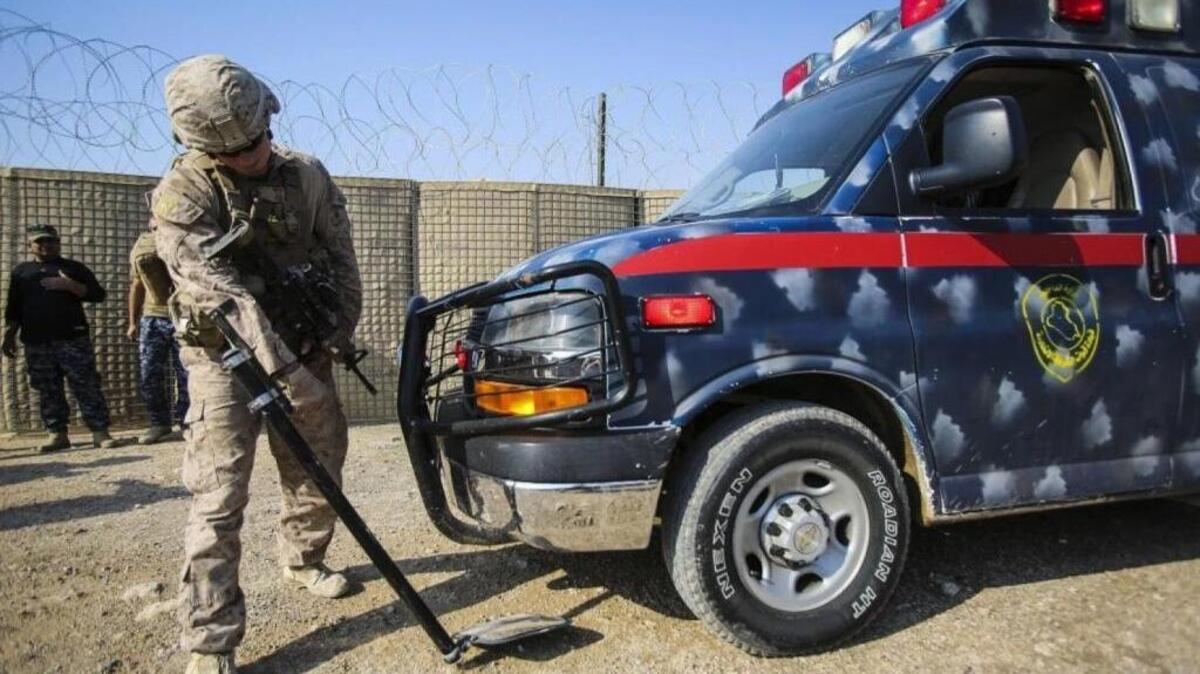 As U.S. involvement in Iraq continues, a U.S. Marine searches an ambulance carrying an injured Iraqi soldier.