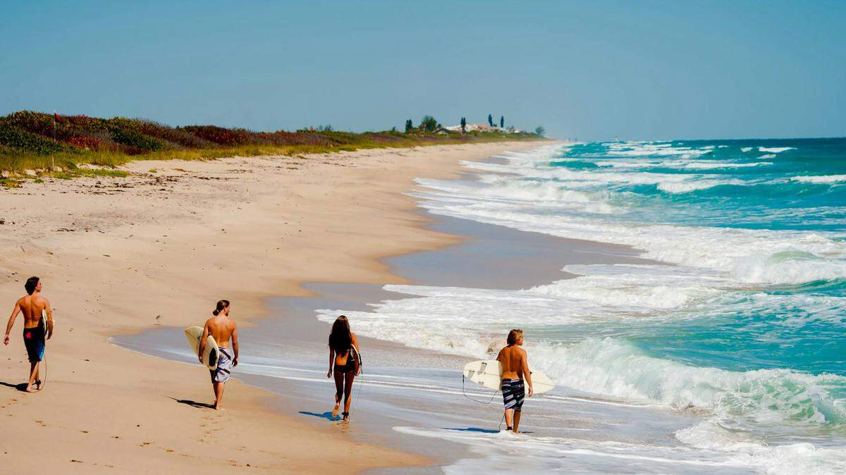 people walking down the beach near Space Coast