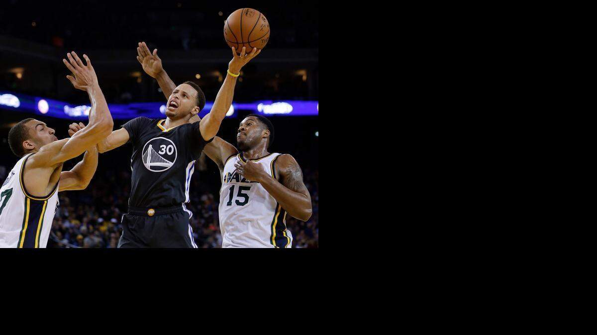 
Golden State Warriors' Stephen Curry, center, shoots between Utah Jazz's Rudy Gobert, left, and Derrick Favors during the second half of an NBA basketball game Saturday, March 21, 2015, in Oakland, Calif. Golden State won 106-91.
