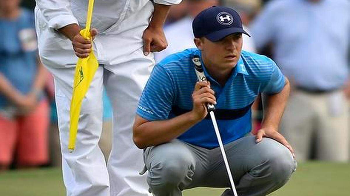 
Jordan Spieth, right, and his caddie Michael Greller, left line up a putt on the 14th green.
