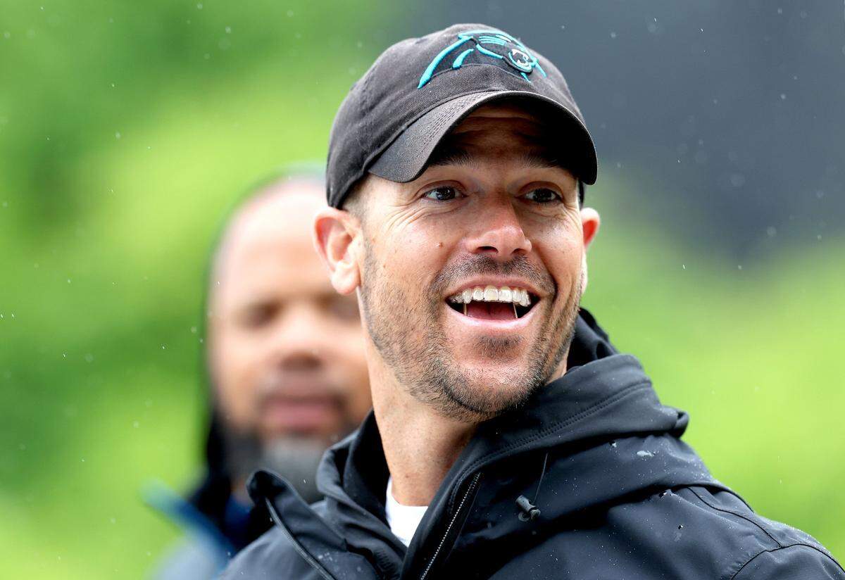 Carolina Panthers head coach Dave Canales smiles as he talks with fans on his walk to the team’s OTA practice on May 27, 2025. 