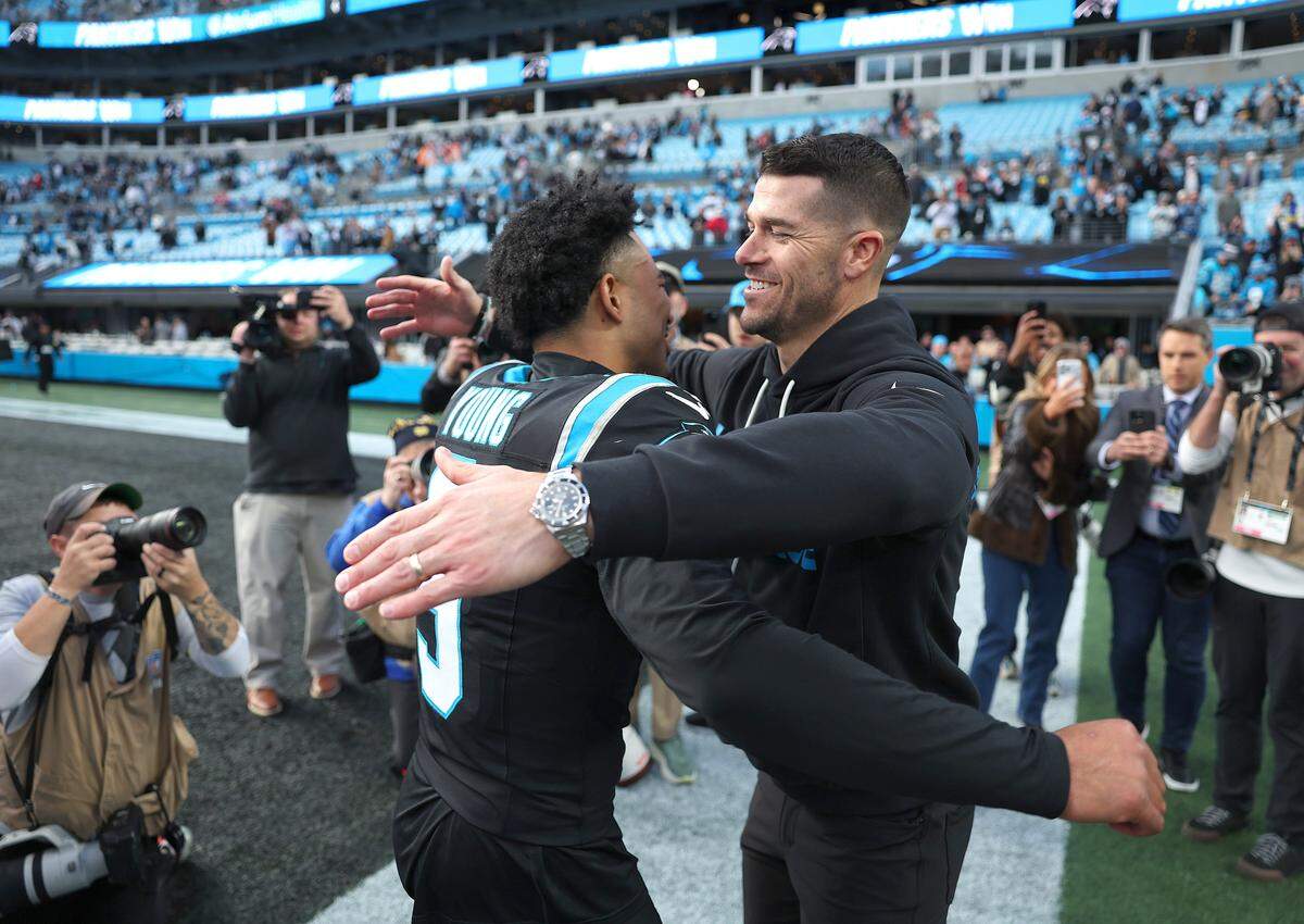 Carolina Panthers quarterback Bryce Young, left and head coach Dave Canales, right, hug following the team's 23-20 victory over the Tampa Bay Buccaneers on Sunday, December 21, 2025 at Bank of America Stadium in Charlotte, NC.