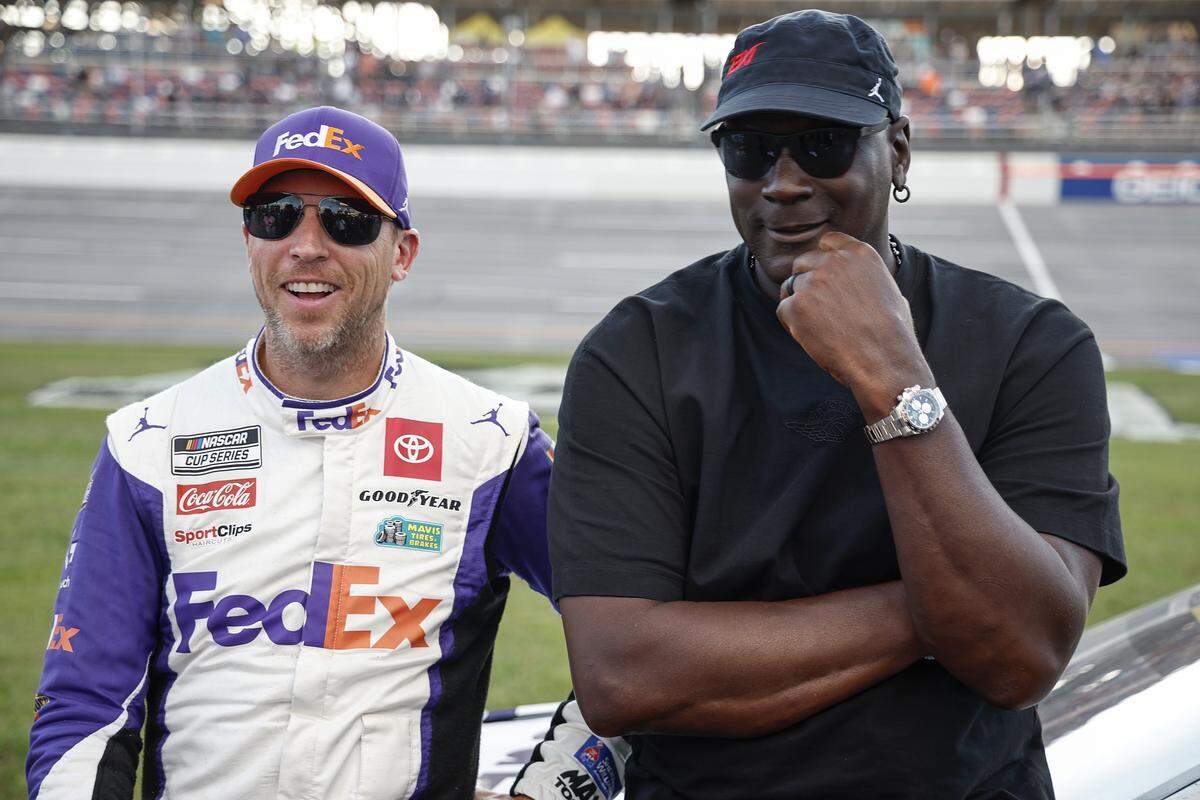 Co-owners of 23XI Racing, Denny Hamlin, driver of the No. 11 FedEx One Rate Toyota, and NBA Hall of Famer, Michael Jordan, talk on the grid after the NASCAR Cup Series YellaWood 500 at Talladega Superspeedway on Oct. 6, 2024, in Talladega, Alabama.