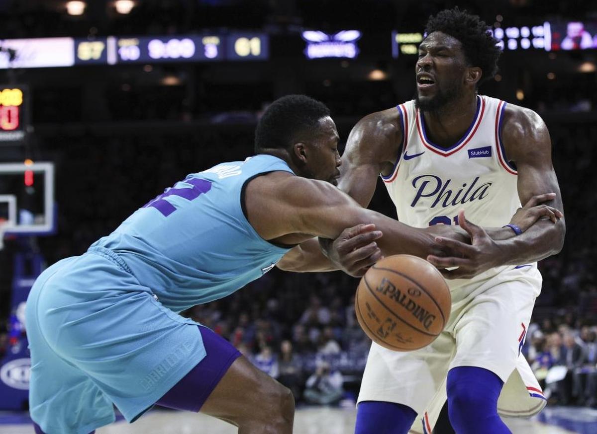 Philadelphia 76ers' Joel Embiid, right, loses the ball as Charlotte Hornets' Dwight Howard fouls him during the second half of Friday’s game.