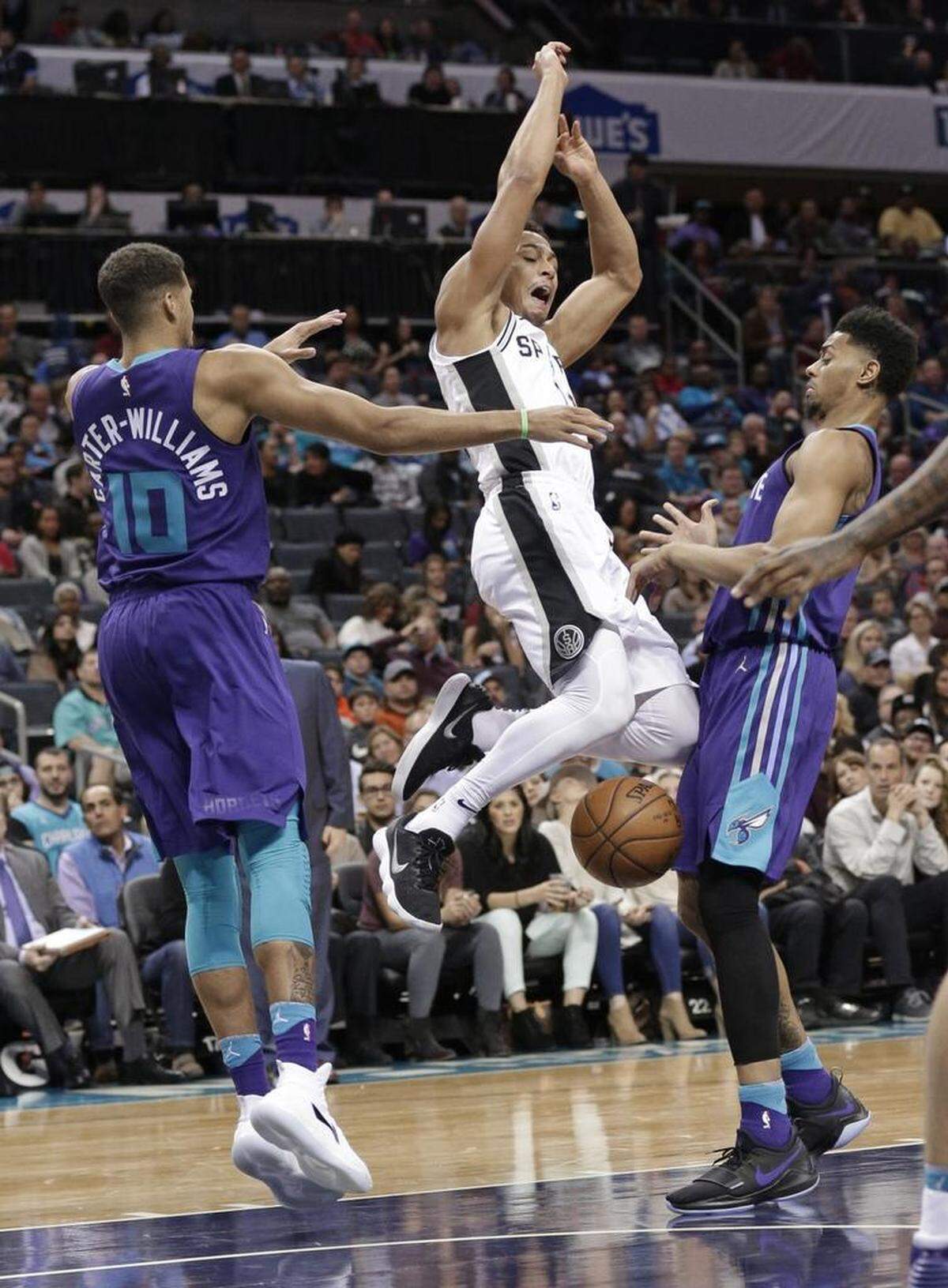 San Antonio Spurs' Kyle Anderson, center, is fouled as he drives between Charlotte Hornets' Michael Carter-Williams, left, and Jeremy Lamb, right, during Saturday’s game.