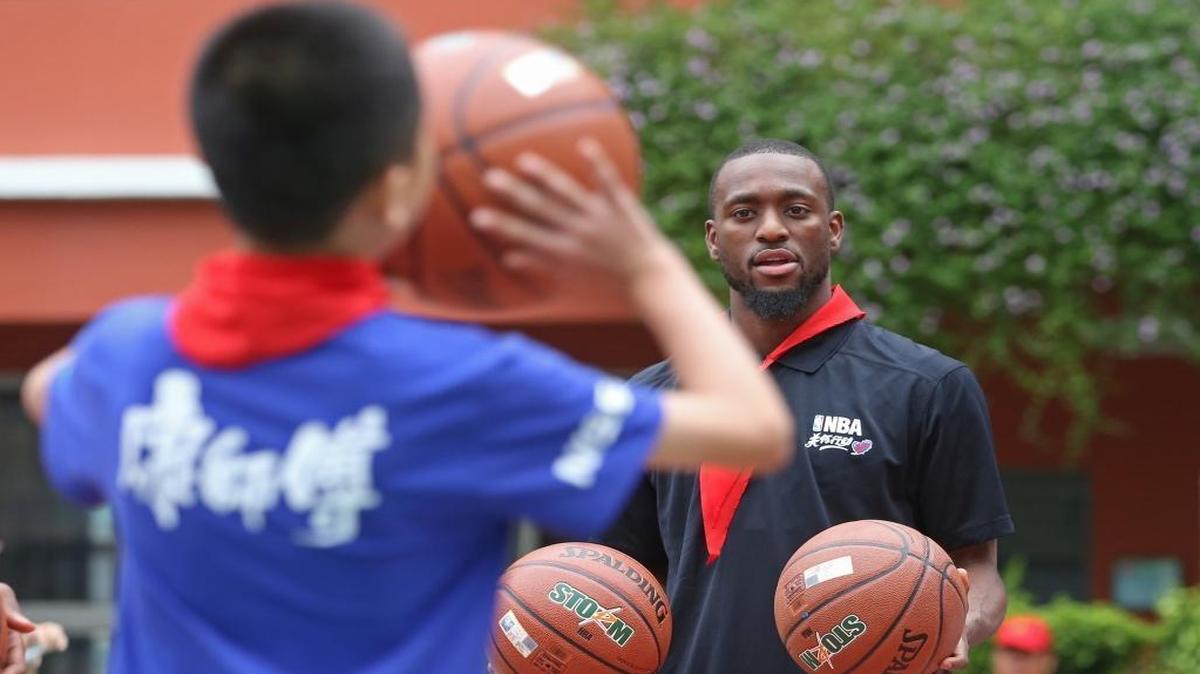 
NBA basketball player Kemba Walker of Charlotte Hornets plays with students at a school for the NBA Care Legacy Project in Shenzhen, south China’s Guangdong province, Saturday. Interest in basketball, and the NBA, among China’s 1.4 billion population is widespread. 
