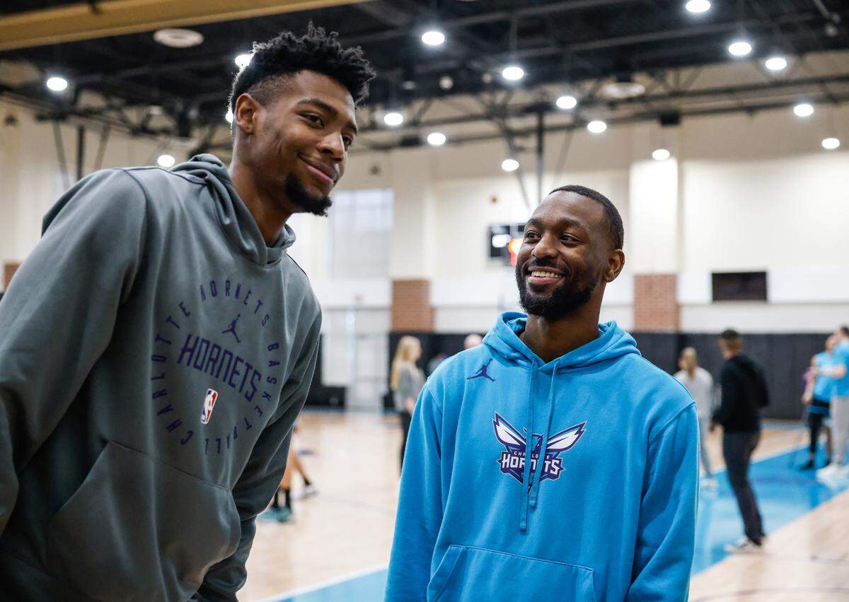 Hornets forward Berandon Miller, left, leans into a photo with former Hornets guard Kemba Walker after team practice at Spectrum Center in Charlotte, NC on Tuesday, December 31, 2024. Now that he is retired, Walker is joining the Hornets coaching staff as a player enhancement coach.