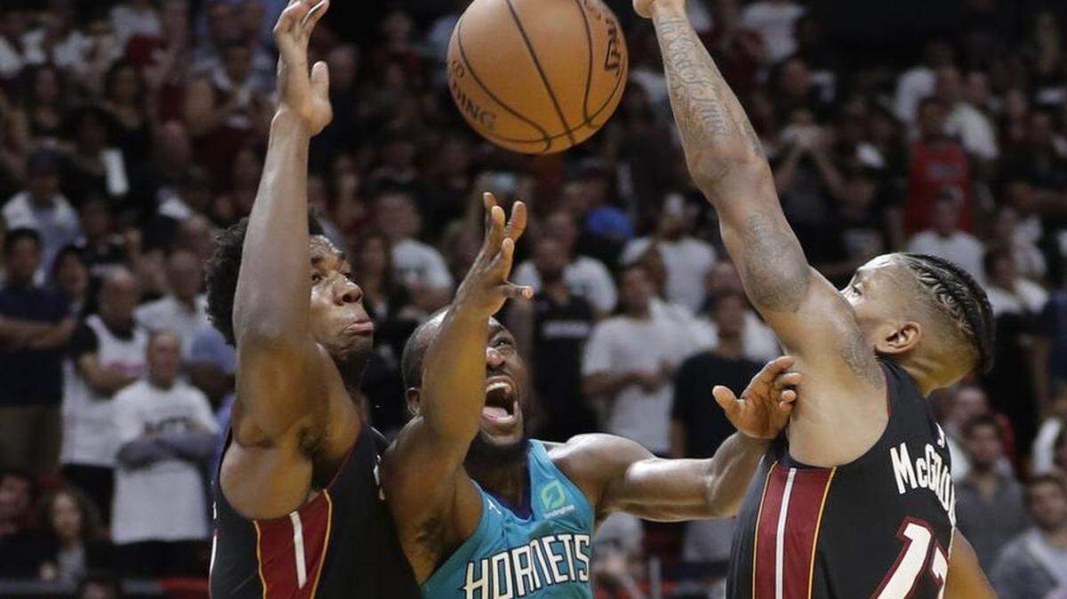 Charlotte Hornets guard Kemba Walker, center, is fouled by Miami Heat guard Rodney McGruder, right, in the closing seconds of Saturday night’s NBA game in Miami. Walker went to the foul line, making the first free throw and intentionally missing the second and time expired. The Hornets won 113-112 to improve to 2-1.