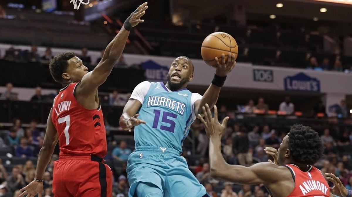 Charlotte Hornets' Kemba Walker (15) drives between Toronto Raptors' Kyle Lowry (7) and OG Anunoby (3) during the first half of Wednesday’s game at Spectrum Center.