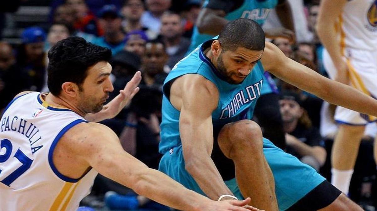 Golden State Warriors center Zaza Pachulia, left and Charlotte Hornets guard Nicolas Batum, right, fight for control of a loose ball during first-quarter action at the Spectrum Center in Charlotteon Wednesday.