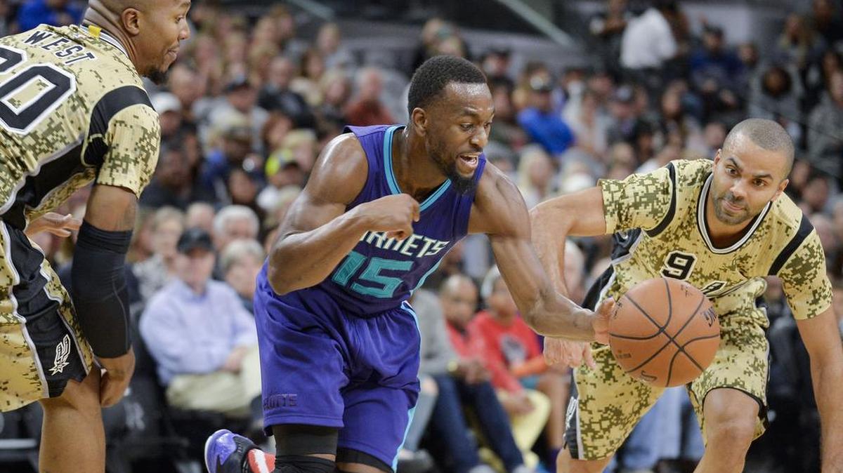 Charlotte Hornets guard Kemba Walker (15) evades San Antonio Spurs' Tony Parker (9), of France, and David West during a Nov. 7 game.