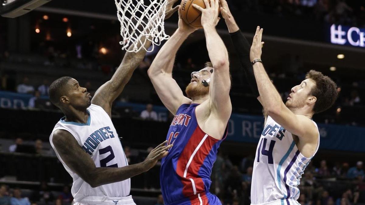 Detroit Pistons' Aron Baynes, center, shoots between Charlotte Hornets' Marvin Williams, left, and Frank Kaminsky III, right, in the second half of an NBA basketball game in Charlotte, N.C., Monday, Dec. 7, 2015. The Hornets won 104-84.