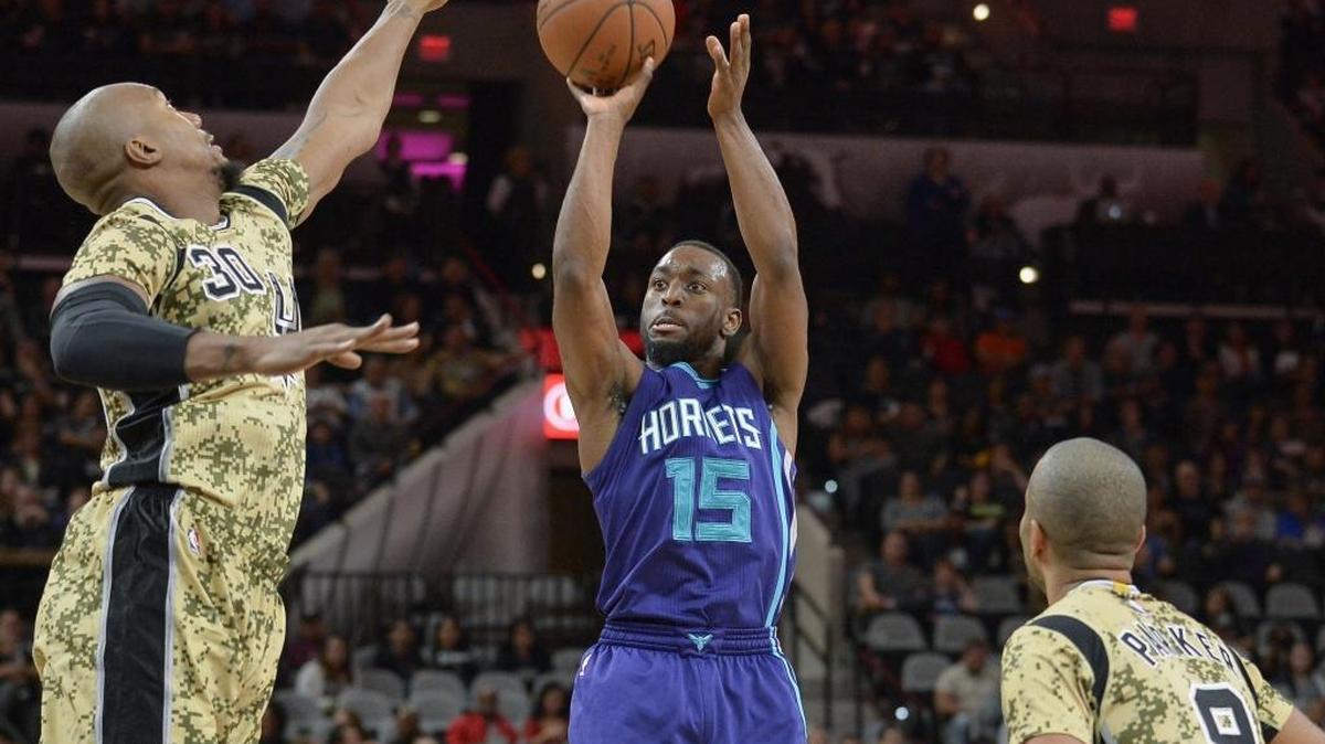 Charlotte Hornets guard Kemba Walker (15) shoots against San Antonio Spurs forward David West (30) and Spurs guard Tony Parker during Saturday’s game.