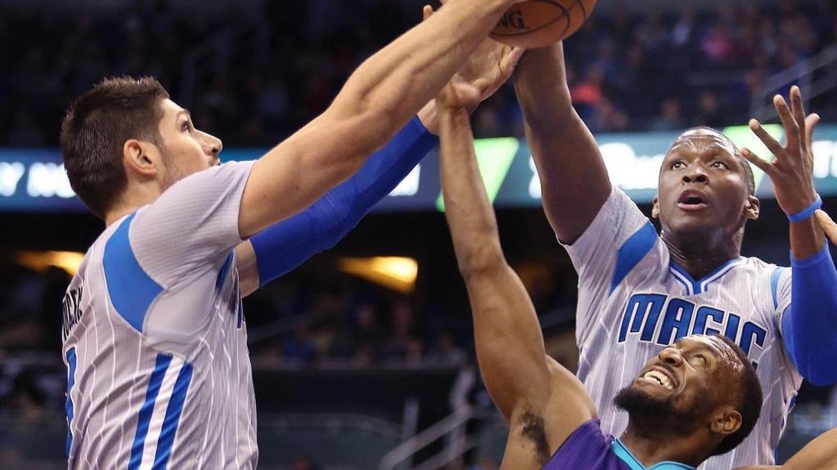 The Orlando Magic's Nikola Vucevic, left, and Victor Oladipo, top right, battle the Charlotte Hornets' Kemba Walker (15) for a rebound at the Amway Center in Orlando, Fla., on Friday.