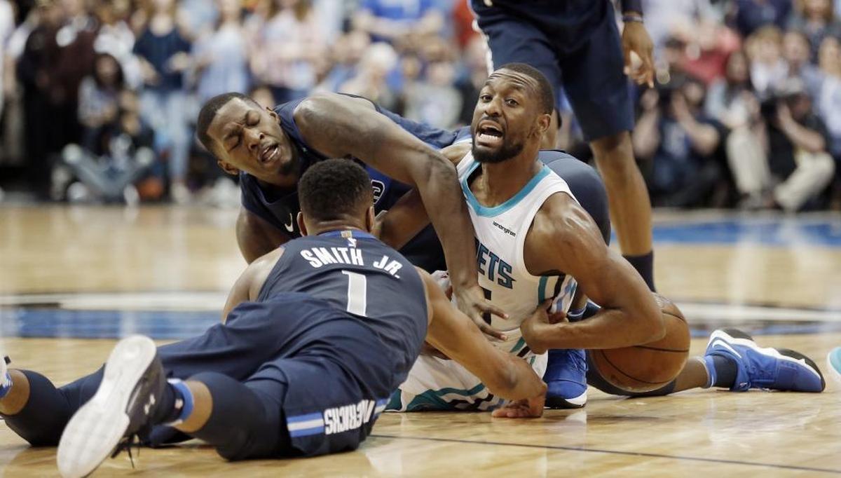 Dallas Mavericks forward Dorian Finney-Smith, background, and guard Dennis Smith Jr. (1) battle Charlotte Hornets guard Kemba Walker (15) for a loose ball during Saturday’s game. Walker scored a game-high 24 points to lead Charlotte to a 102-98 win.