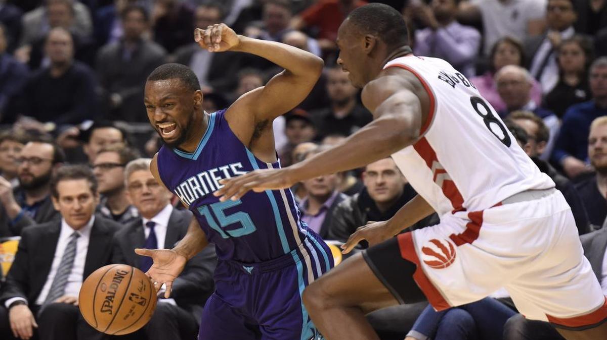 The Charlotte Hornets’ Kemba Walker (15) fights to control the ball as the Toronto Raptors’ Bismack Biyombo (8) defends during the second half Tuesday in Toronto. The Raptors won, 96-90.