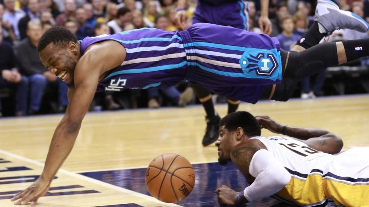 Charlotte Hornets guard Kemba Walker leaps over Indiana Pacers forward Paul George as they chase a loose ball during Wednesday’s game. Charlotte won 96-95.
