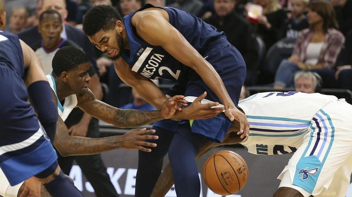 Minnesota Timberwolves center Karl-Anthony Towns (32) fights for a loose ball with Charlotte Hornets guard Dwayne Bacon, left, and Marvin Williams, right, in the first half of Sunday’s game in Minneapolis. The Wolves won 112-94.