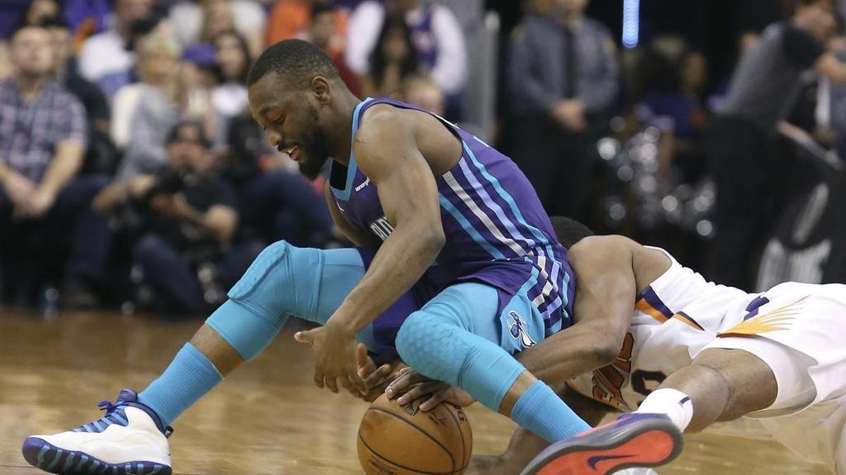 Charlotte Hornets guard Kemba Walker, left, and Phoenix Suns’ T.J. Warren battle for the ball during the first half of Sunday’s game. Walker set a franchise record for 3-pointers made the 115-110 road.