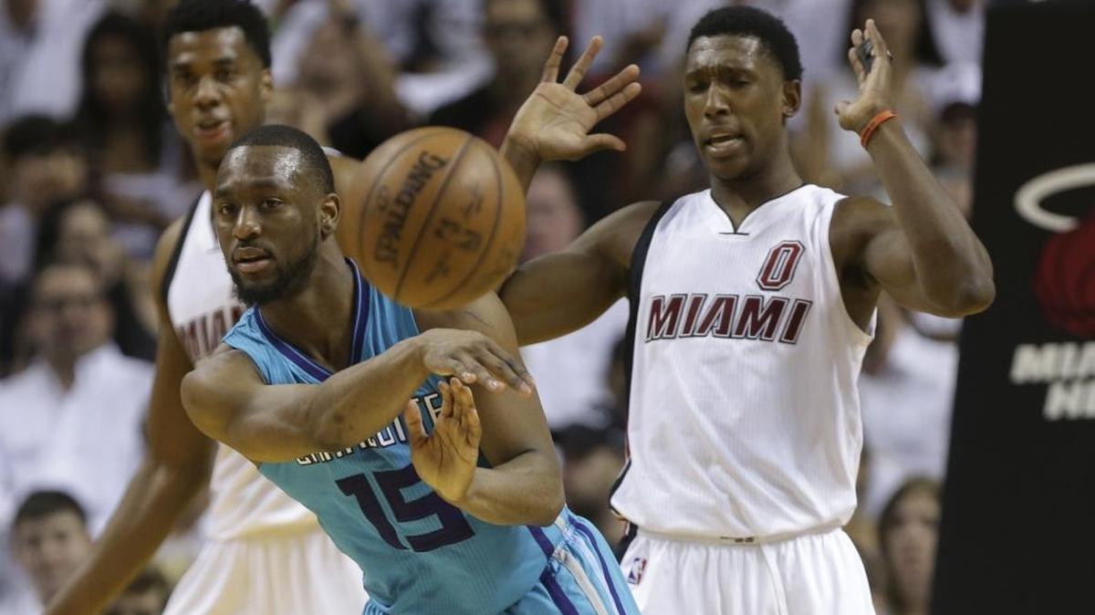 Charlotte Hornets guard Kemba Walker (15) passes in front of Miami Heat guard Josh Richardson (0) during the second half of Game 1 of a first-round NBA basketball playoff series, Sunday, April 17, 2016, in Miami. The Heat defeated the Hornets 123-91.