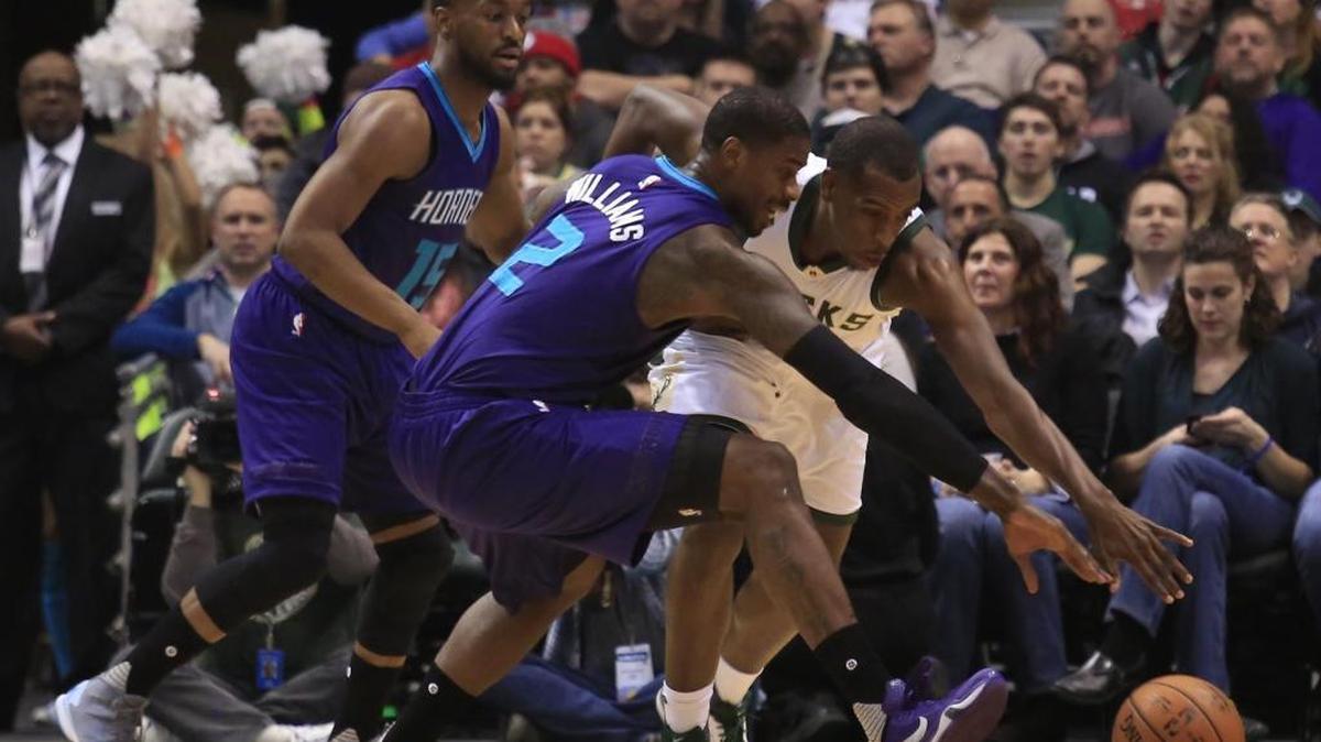 Charlotte Hornets forward Marvin Williams, front, battles for the ball with Milwaukee Bucks guard Khris Middleton, right, during the first half of Friday’s game in Milwaukee.