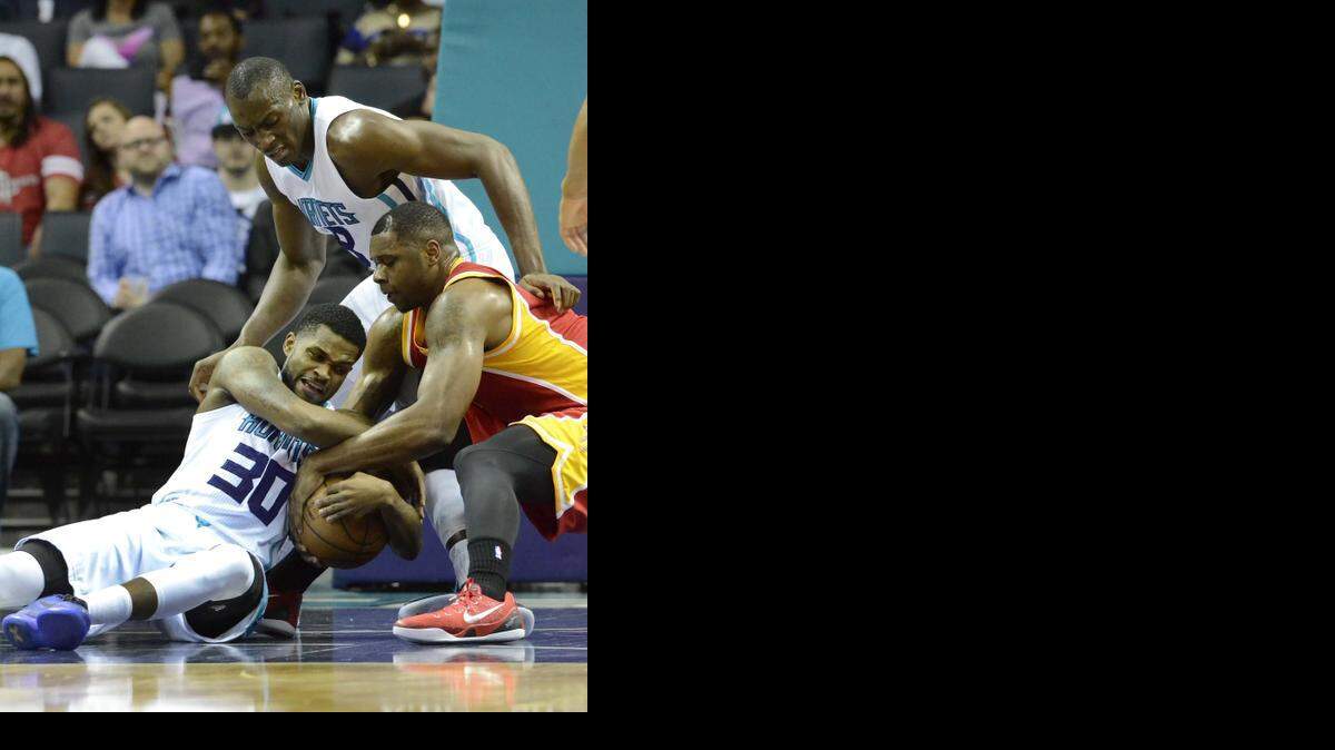 
 Charlotte Hornets Troy Daniels (left), fights for control of the ball with Houston Rockets Terrence Jones (right), Charlotte Hornets Bismack Biyombo (center), during Monday night's game played at Time Warner Cable Arena, April 13, 2015.
