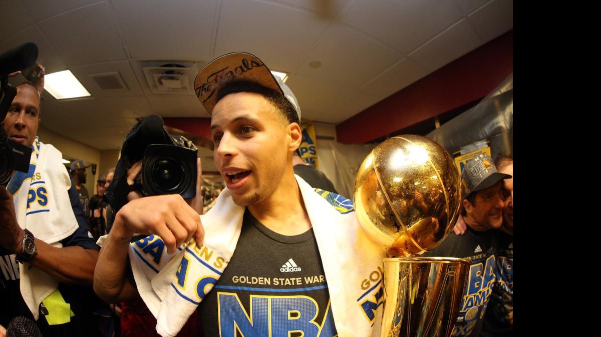 
Golden State point guard Stephen Curry celebrates with the Larry O'Brien Trophy in the locker room after the Warriors beat Cleveland 105-97 in Game 6 of the NBA Finals to win the league title. Curry, his family, teammates and fiends celebrated until about 5 a.m. Thursday.
