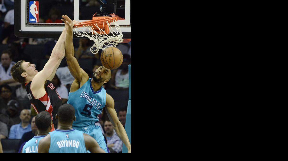 
 Toronto Raptors Tyler Hansbrough(left), dunks the ball against Charlotte Hornets Gerald Henderson (right), during Wednesday night's game played at Time Warner Cable Arena April 8 ,2015.
