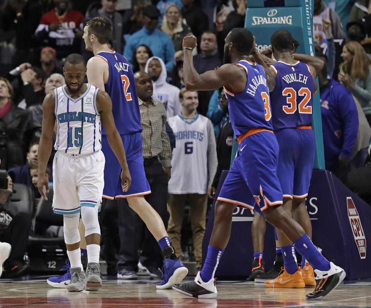 New York’s players celebrate as Charlotte Hornets guard Kemba Walker (15) walks away after the Knicks' 126-124 overtime win Friday night at Spectrum Center.