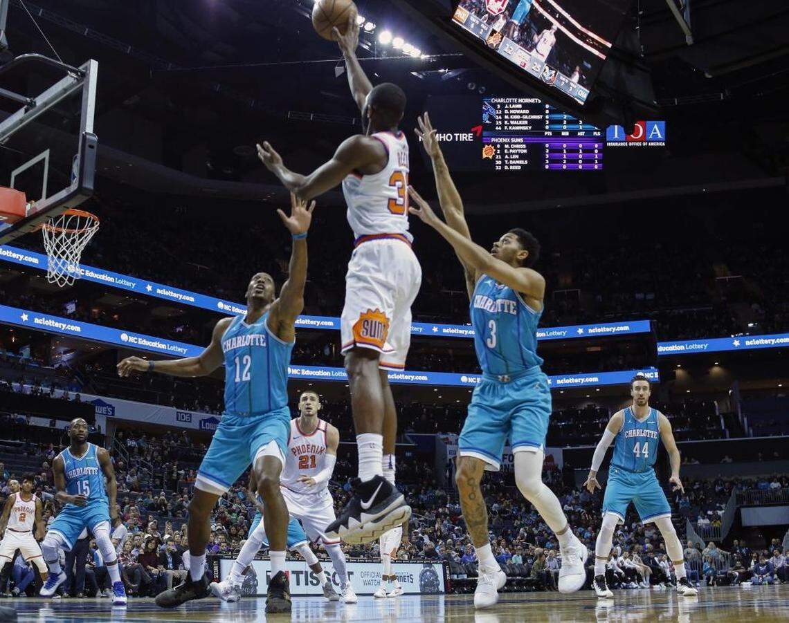 Phoenix Suns guard Davon Reed, center, shoots over the double team by Charlotte Hornets center Dwight Howard (12) and guard Jeremy Lamb in the first half of Saturday’s game. The Hornets let a 22-point lead slip all the way to two late in Saturday’s game but were able to win 122-115 to end a five-game losing streak.