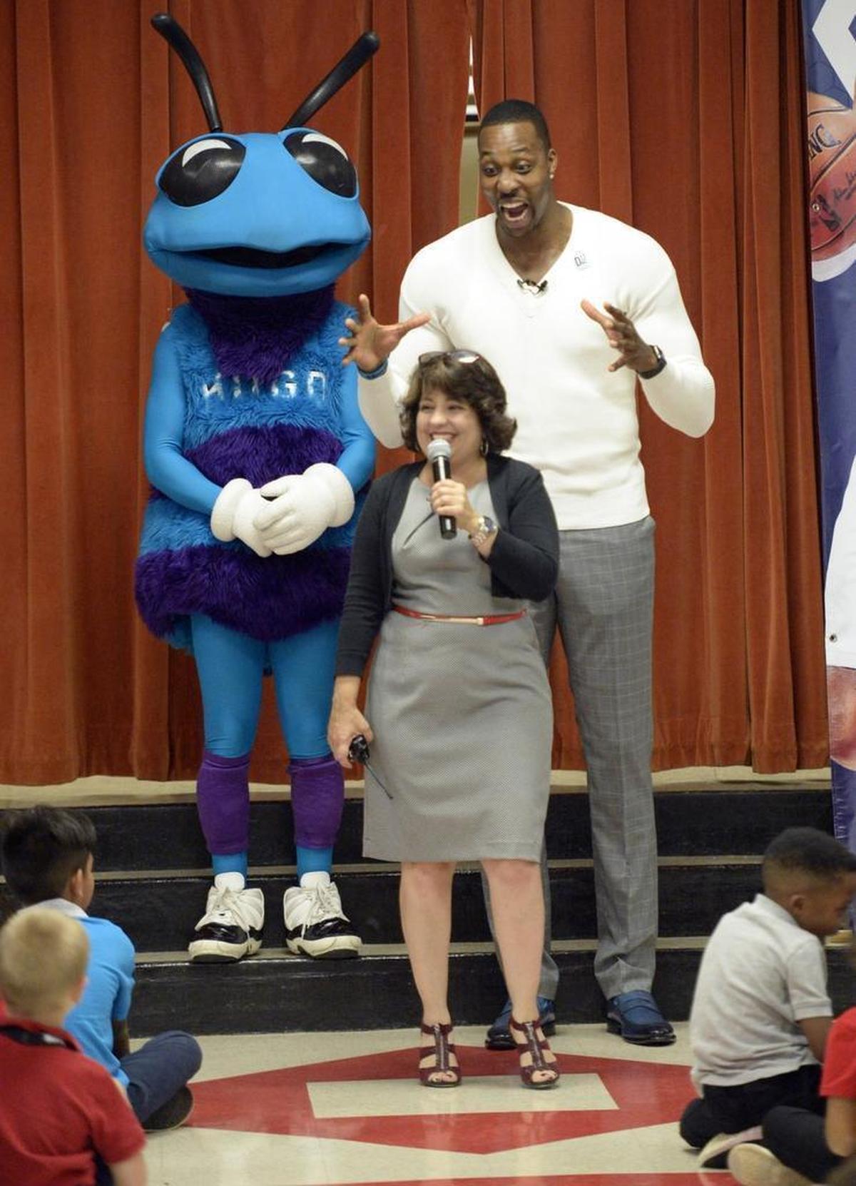 Charlotte Hornets center Dwight Howard is playful behind Principal Nancy Martinez, to the delight of students, while making a visit in September to Starmount Academy of Excellence.