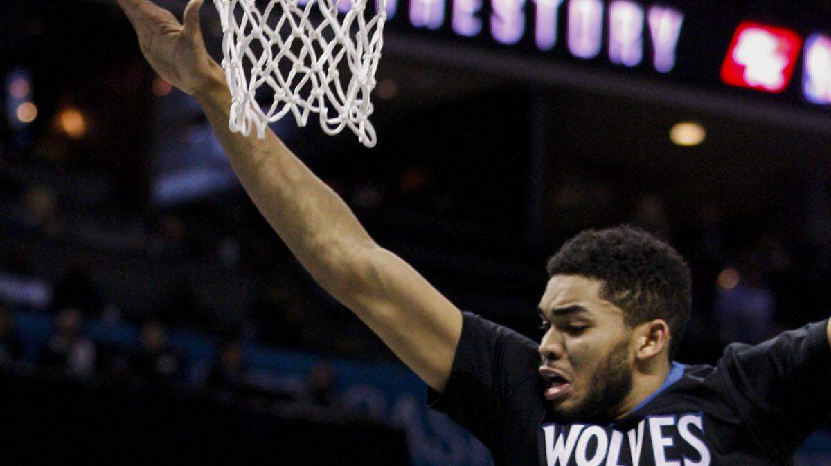 Charlotte Hornets guard Kemba Walker, left, passes around Minnesota Timberwolves center Karl-Anthony Towns in the first half of an NBA basketball game in Charlotte, N.C., Monday, March 7, 2016. (AP Photo/Nell Redmond)