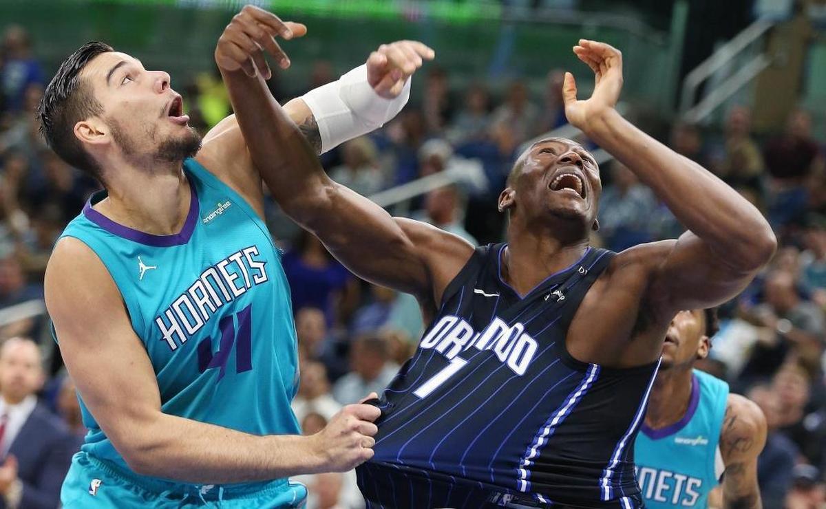 The Charlotte Hornets' Willy Hermangomez (41) pulls the jersey of the Orlando Magic's Bismack Biyombo (11) in a battle for a rebound during Friday’s game. The Hornets routed the Magic, 137-100.
