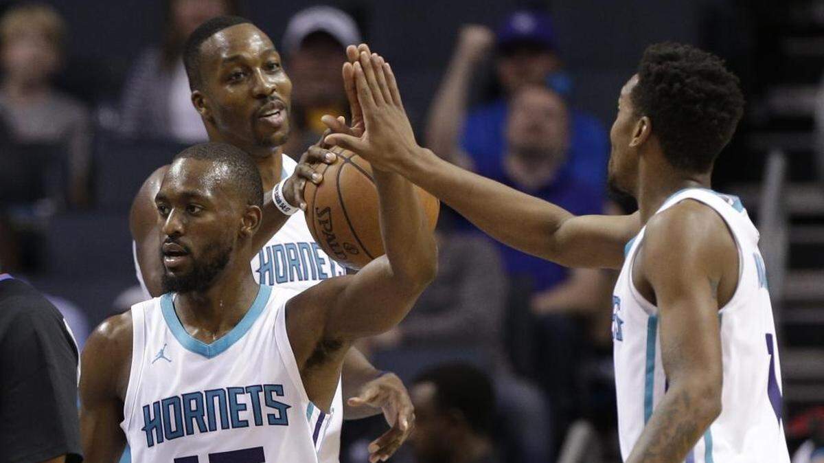 Charlotte Hornets center Dwight Howard, back, and shooting guard Malik Monk, right, congratulate point guard Kemba Walker, front, after a basket against the Dallas Mavericks in Friday’s preseason game.