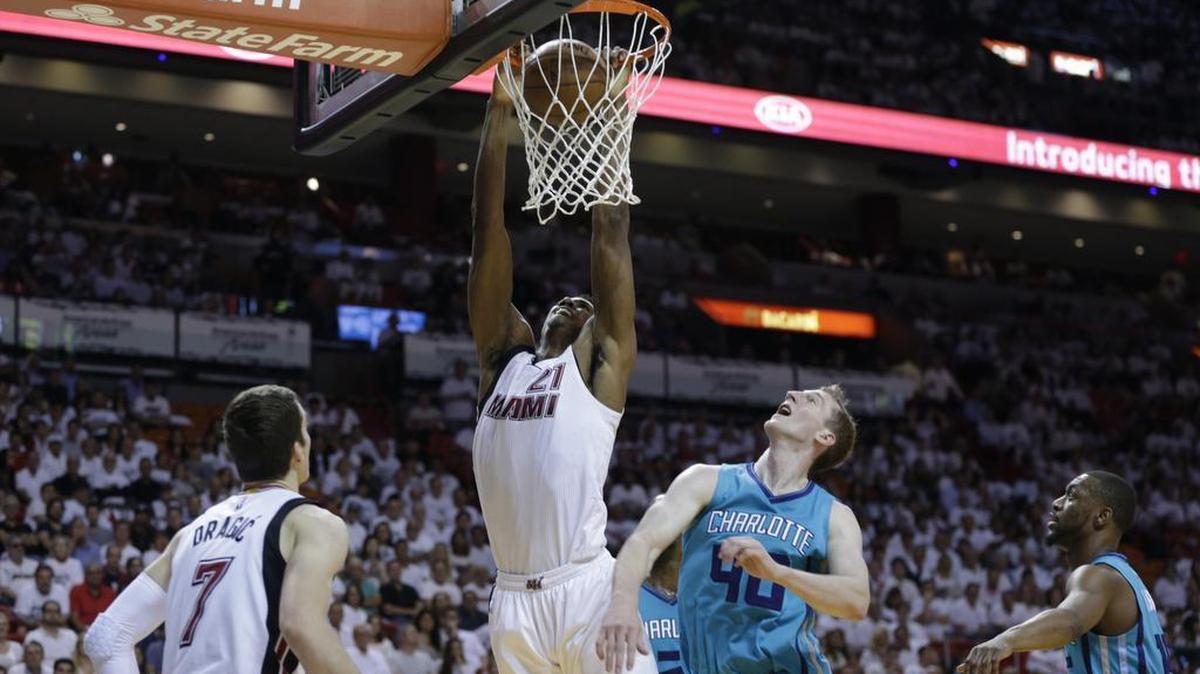Miami Heat center Hassan Whiteside (21) dunks over Charlotte Hornets center Cody Zeller (40) and guard Kemba Walker, right, during the second half of Game 1 of a first-round NBA basketball playoff series, Sunday in Miami. The Heat defeated the Hornets 123-91.