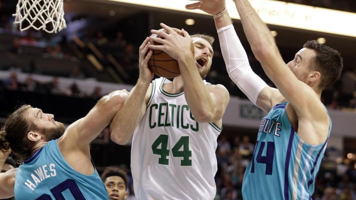 Boston Celtics' Tyler Zeller, center, is fouled as he drives between Charlotte Hornets' Spencer Hawes, left, and Frank Kaminsky III, right, in the first half of Saturday’s NBA game in Charlotte. The Celtics beat the Hornets, 104-98.