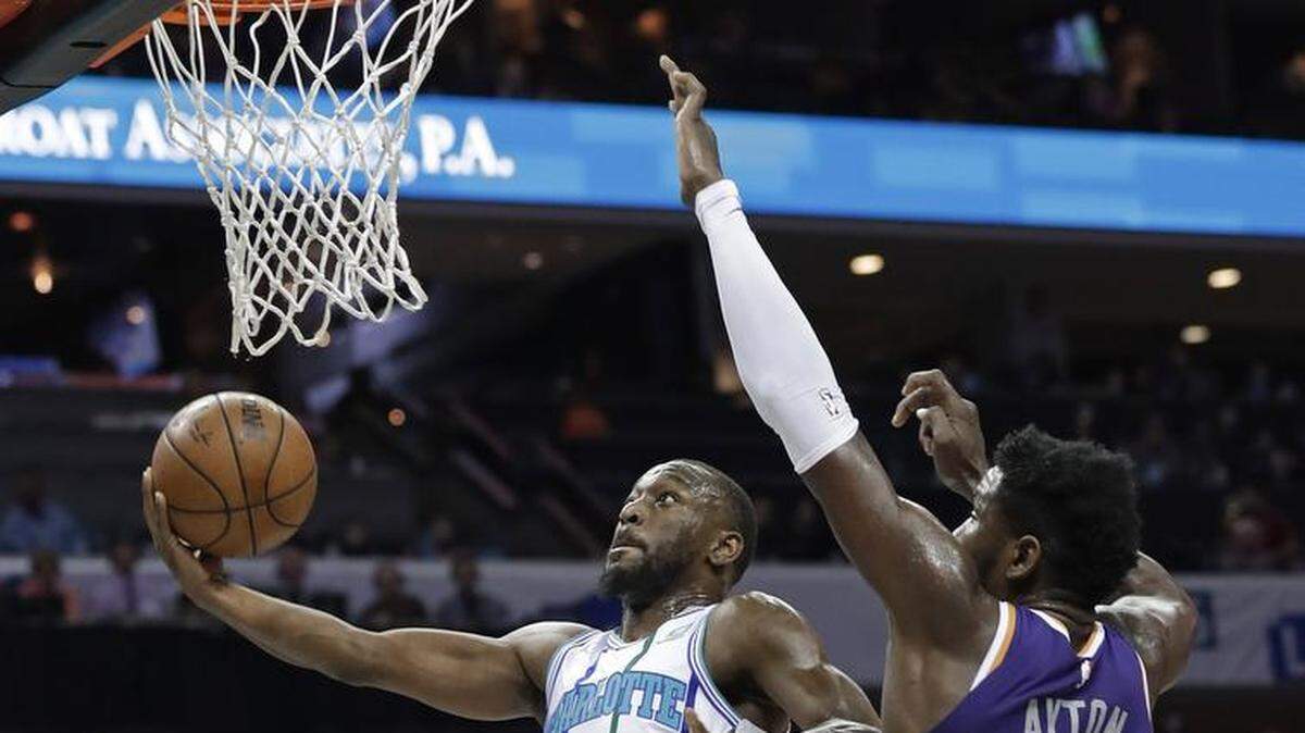 Charlotte Hornets’ Kemba Walker (15) drives past Phoenix Suns’ Deandre Ayton (22) during the first half of an NBA basketball game in Charlotte, N.C., Saturday, Jan. 19, 2019. (AP Photo/Chuck Burton)
