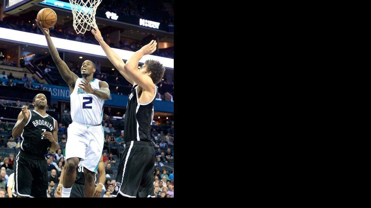 
 Charlotte Hornets forward (center) carries the ball to the basket against Brooklyn Nets Brook Lopez (right) during Wednesday night's game played at Time Warner Cable Arena, March 25, 2015.
