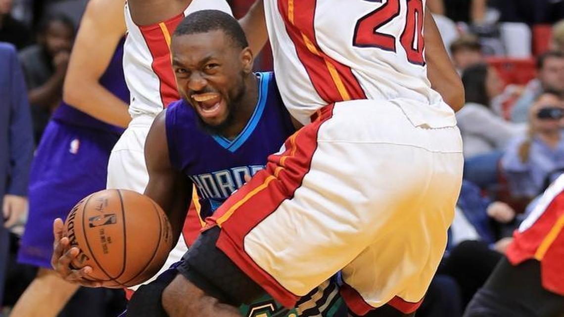 Charlotte Hornets guard Kemba Walker, center, drives on the Miami Heat’s Justise Winslow (20) during Friday night’s game in Miami.
