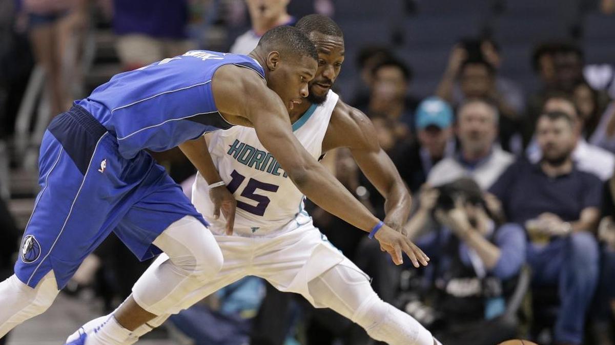 Charlotte Hornets' Kemba Walker (15) and Dallas Mavericks' Dennis Smith Jr. (1) chase a loose ball in the first half of a preseason exhibition Friday night at Spectrum Center.