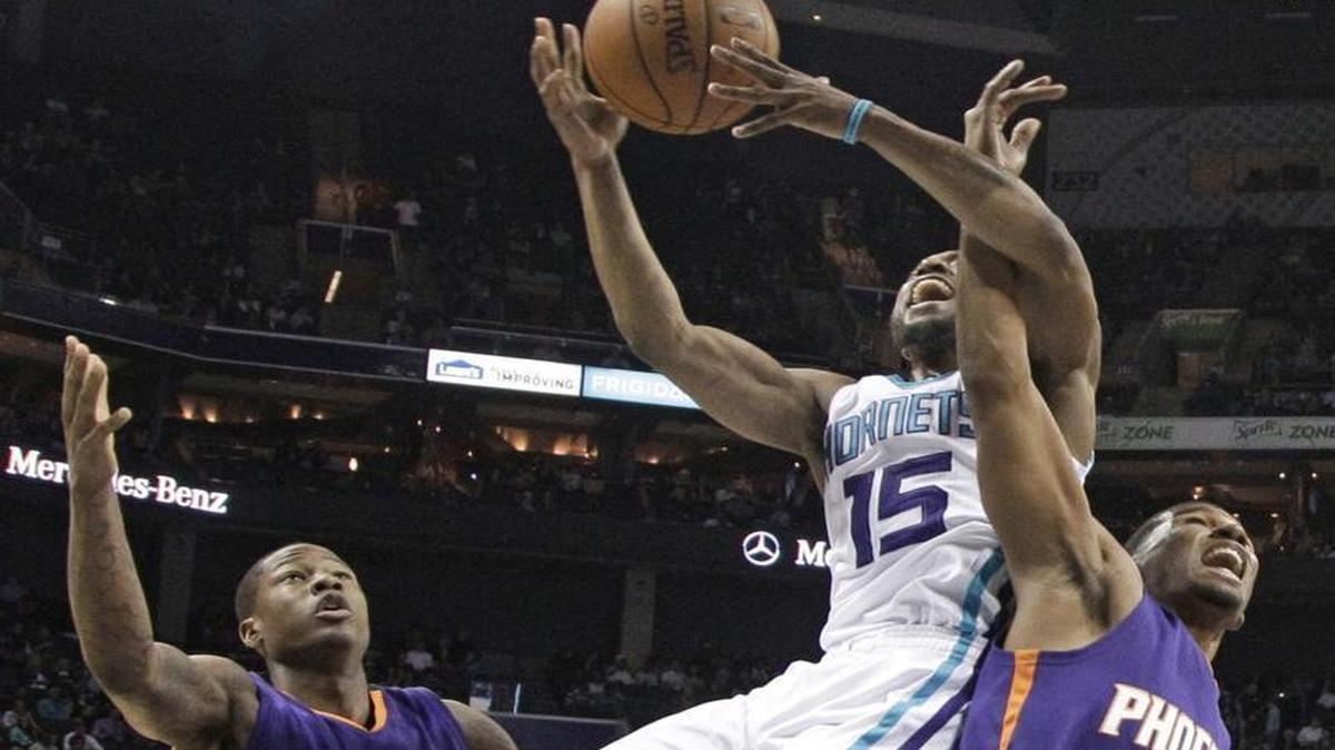 Charlotte Hornets' Kemba Walker (15) is fouled as he drives between Phoenix Suns' Archie Goodwin (20) and Ronnie Price during the first half of an NBA basketball game in Charlotte, Tuesday, March 1, 2016.