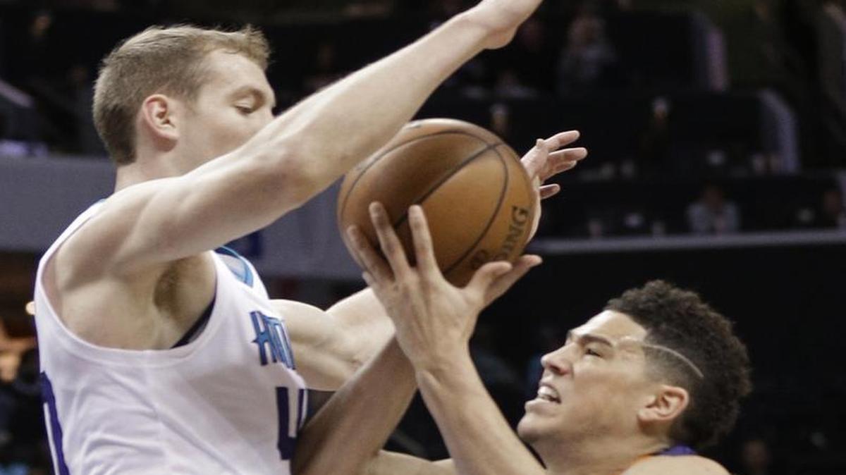 Phoenix Suns' Devin Booker, right, drives against Charlotte Hornets' Cody Zeller, left, in the first half of Sunday’s game. The Hornets defense held Devin Booker to 47 fewer points than he scored Friday against Celtics.