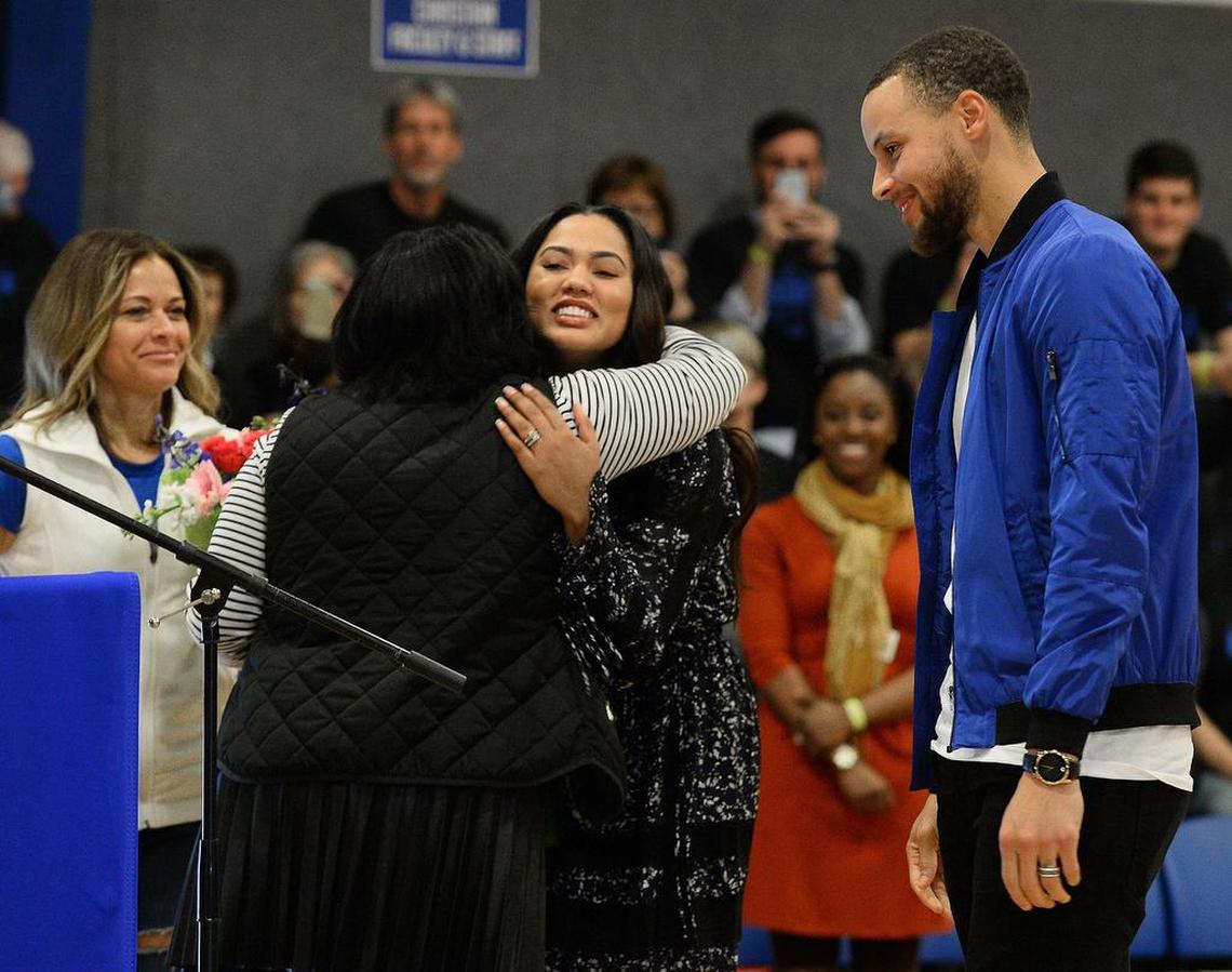 NBA star Steph Curry, right, looks on as his wife, Ayesha, center, is hugged during a ceremony retiring his high school jersey, No. 20, at Charlotte Christian on Jan. 24, 2017.
