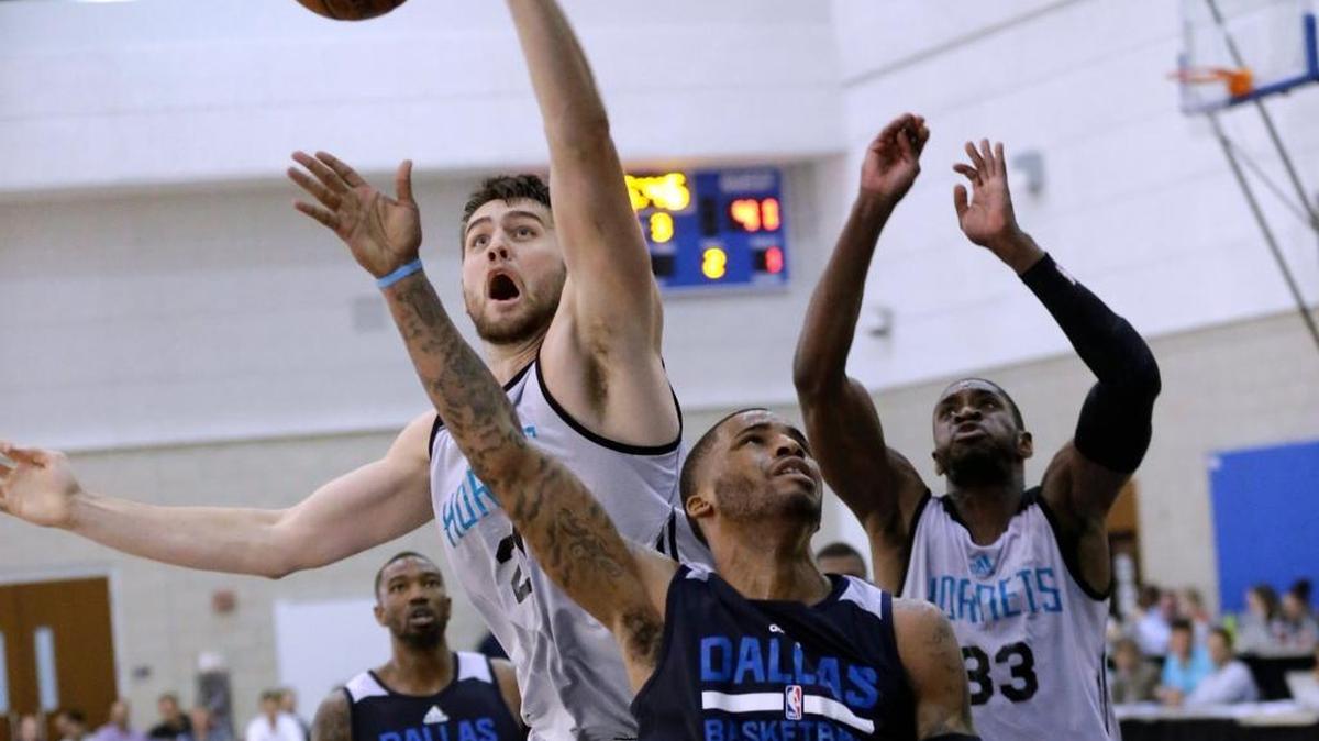 Center Mike Tobey, blocking a shot by Dallas Mavericks' Vander Blue (13), will be in the Hornets training camp in October.
