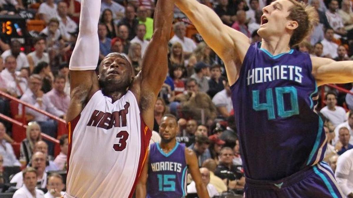 The Miami Heat’s Dwyane Wade fights for a loose ball with the Charlotte Hornets’ Cody Zeller in Wednesday’s season-opener. The Heat won, 104-94.
