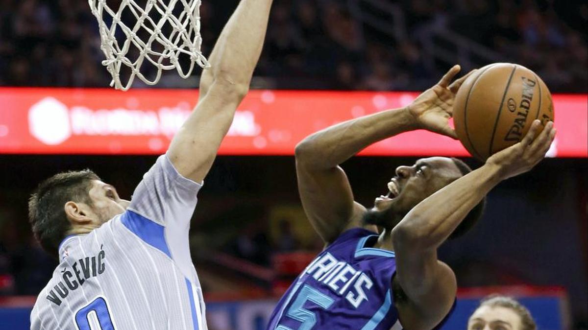 Charlotte Hornets guard Kemba Walker, front right, attempts to shoot over Orlando Magic center Nikola Vucevic (9) during the first half of an NBA basketball game, Friday in Orlando, Fla.