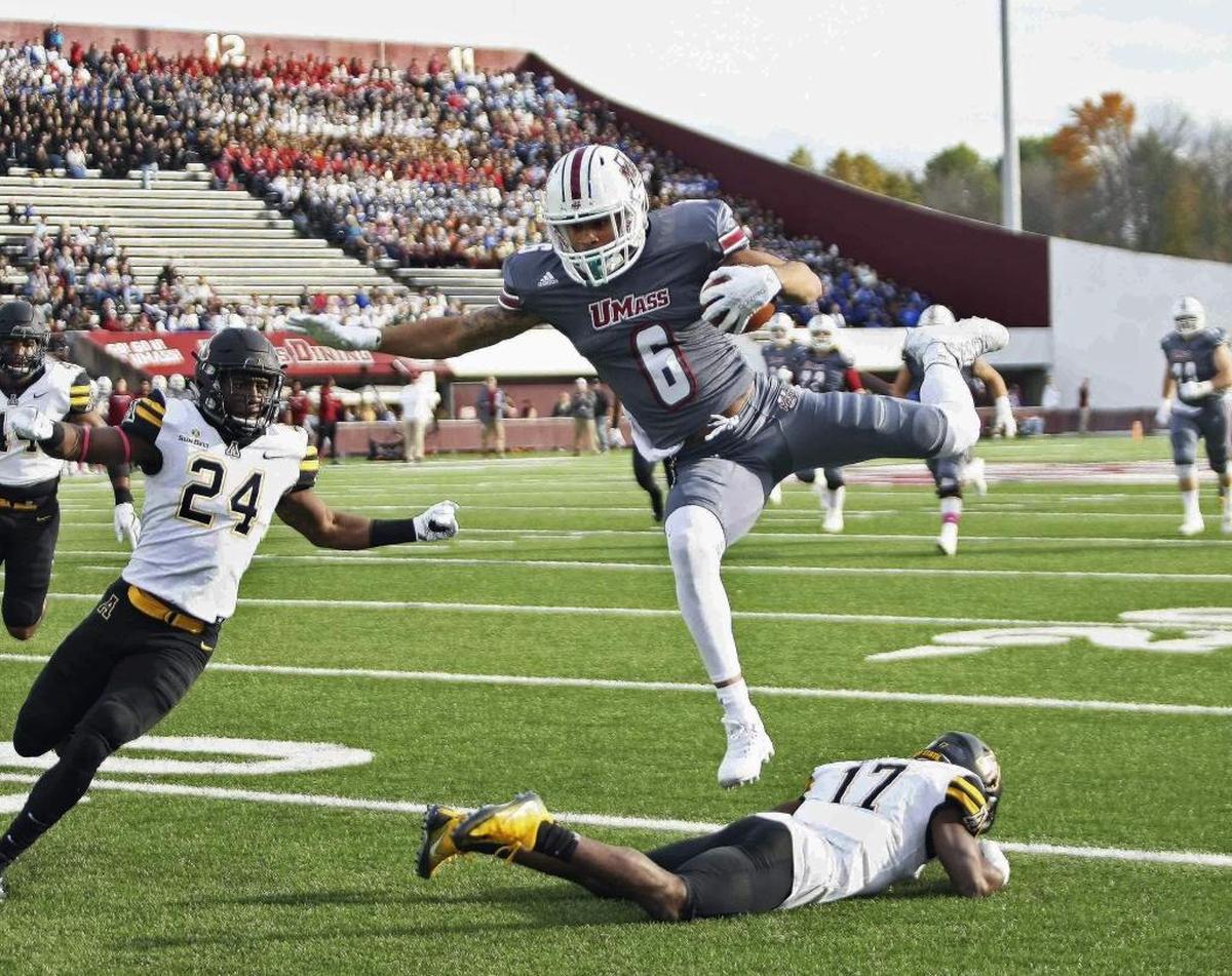 Massachusetts’ Sadiq Palmer hurdles over Appalachian State’s Tea Hayes as Akeem Davis-Gaither, left, looks on during the first quarter of Saturday’s game. UMass won 30-27 in two overtimes.
