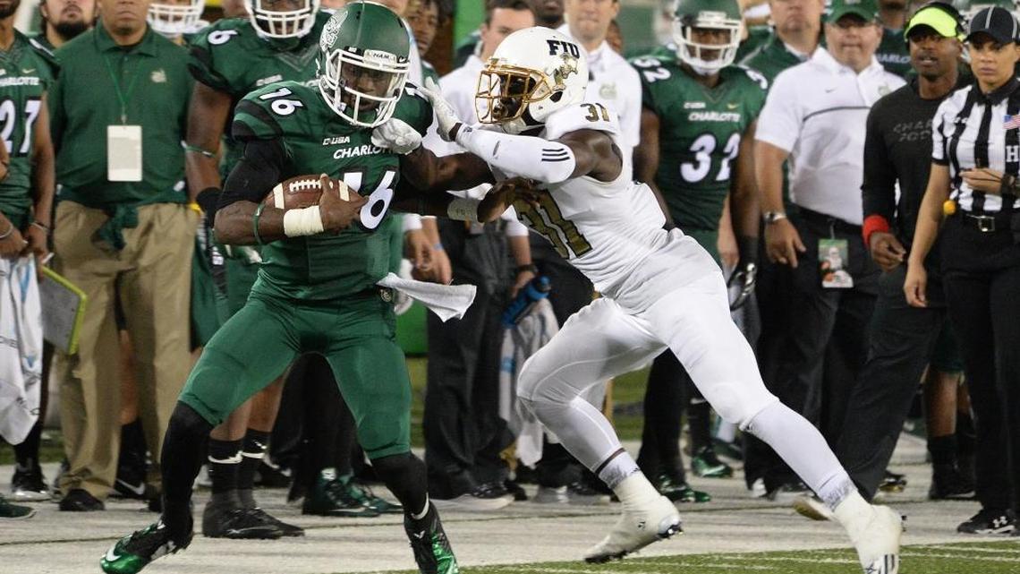 Charlotte quarterback Hasaan Kluge (16) fends off FIU defender Tyree Johnson during Saturday’s Conference USA game at Richardson Stadium.