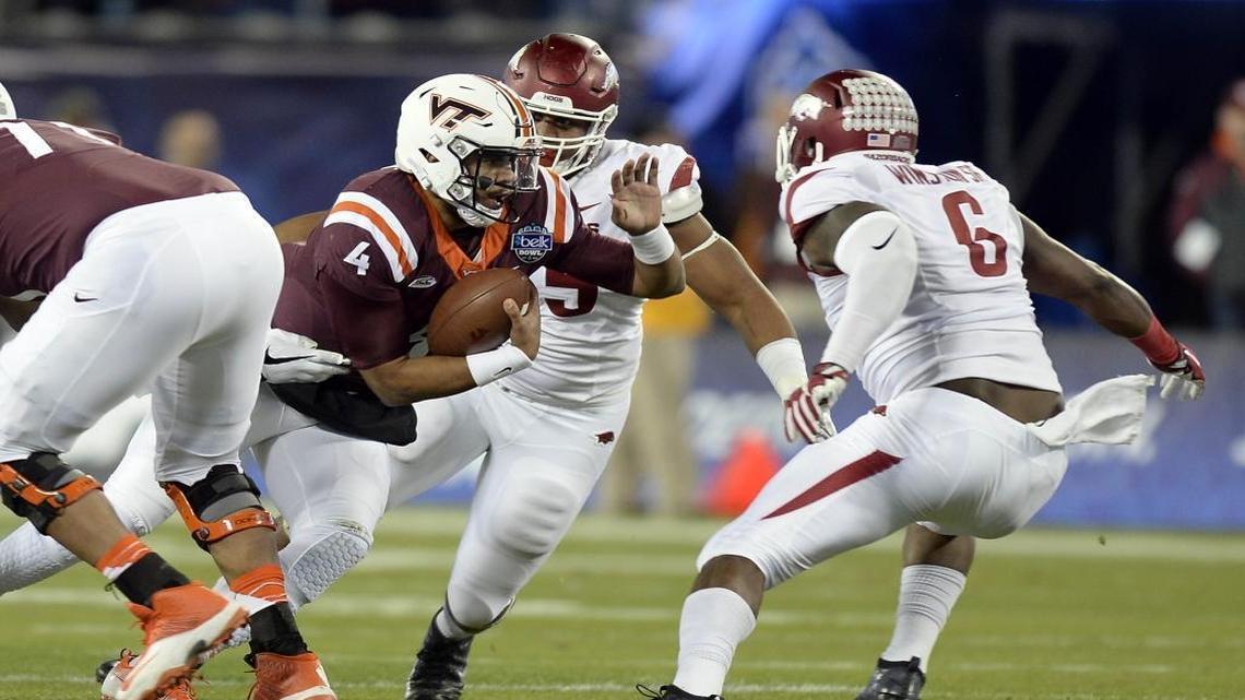 Virginia Tech quarterback Jerod Evans (4) looks for running room against Arkansas defensive lineman JaMichael Winston (6) during the first half of the Belk Bowl at Bank of America Stadium on Thursday night. The Hokies rallied from a 24-0 halftime deficit to win 35-24.