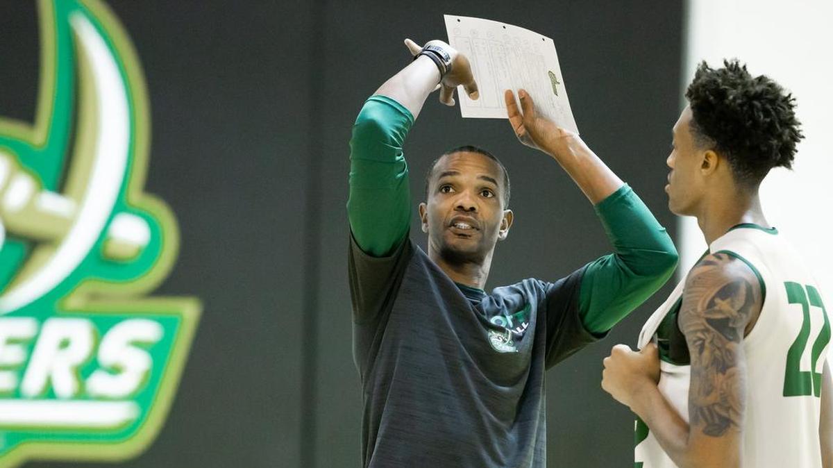 First-year coach Ron Sanchez gives some shooting tips to Charlotte 49ers freshman guard Brandon Younger during the 49ers’ first practice of the season.